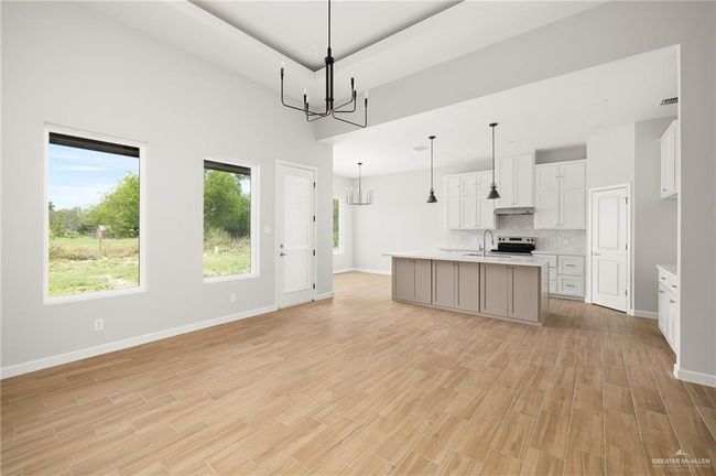 Kitchen with light wood-style floors, tasteful backsplash, light countertops, a sink, and a notable chandelier | Image 4