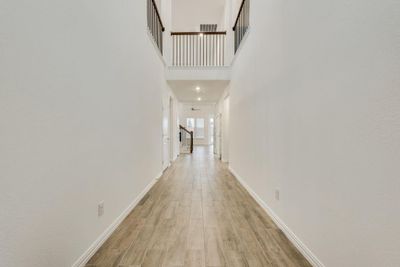 Hallway with light wood-type flooring and a towering ceiling | Image 2