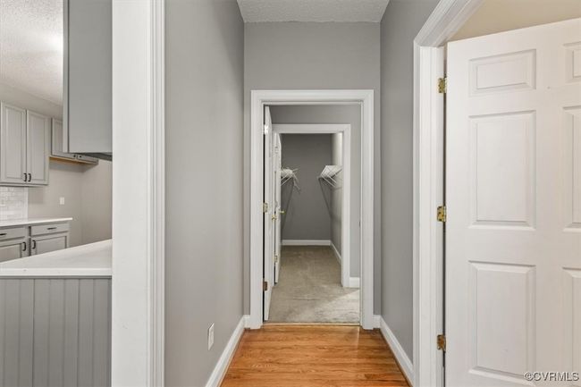 Hallway with a textured ceiling, baseboards, and light wood finished floors | Image 25