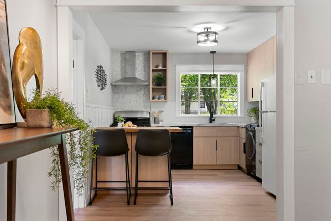 The kitchen features Corian/Wooden countertops and a stylish tile backsplash throughout. | Image 7