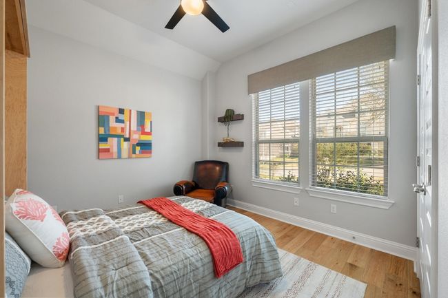 This front of the house bedroom has a Murphy bed, ceiling fan, simple shelving and oversized windows. | Image 27