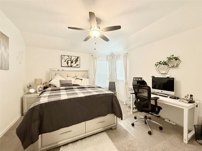 Bedroom with light colored carpet, an office area, and ceiling fan | Image 37