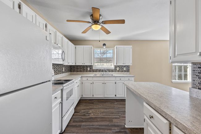 Kitchen featuring tasteful backsplash, white appliances, light countertops, and a sink | Image 10
