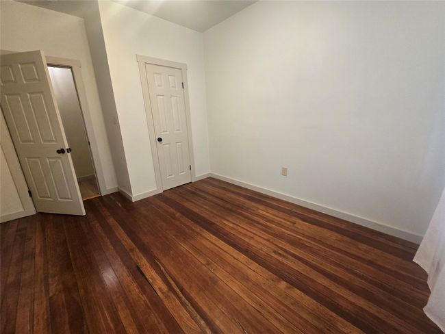 Unfurnished bedroom featuring dark wood-type flooring and baseboards | Image 13