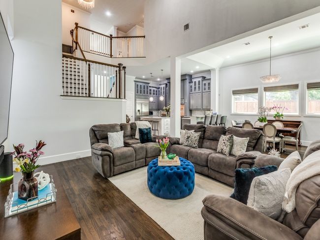 Living area featuring wood finished floors, a towering ceiling, baseboards, and stairs | Image 9