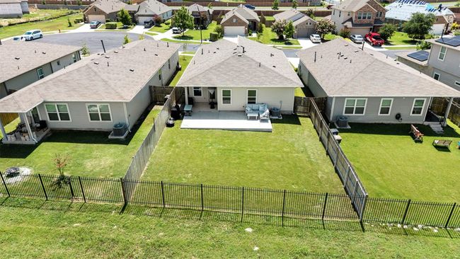 An elevated view of the backyard, showcasing the large grassy area, privacy fence, and covered patio, making it an ideal space for outdoor living and relaxation. | Image 31