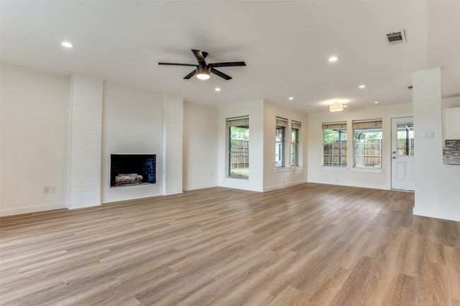 Unfurnished living room with ceiling fan, light wood-style flooring, recessed lighting, a brick fireplace, and baseboards | Image 4