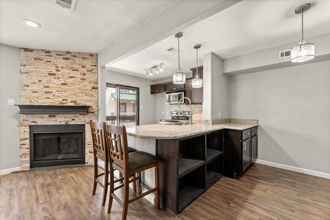 Kitchen featuring open shelves, light stone countertops, dark wood-type flooring, a peninsula, and a textured ceiling | Image 14