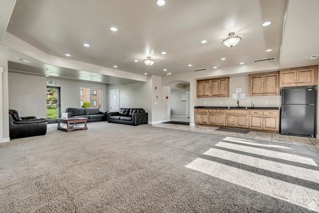 Living room featuring arched walkways, light carpet, recessed lighting, and bar with sink | Image 10