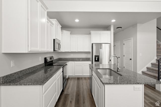 Kitchen with stainless steel appliances, white cabinetry, an island with sink, and recessed lighting | Image 13