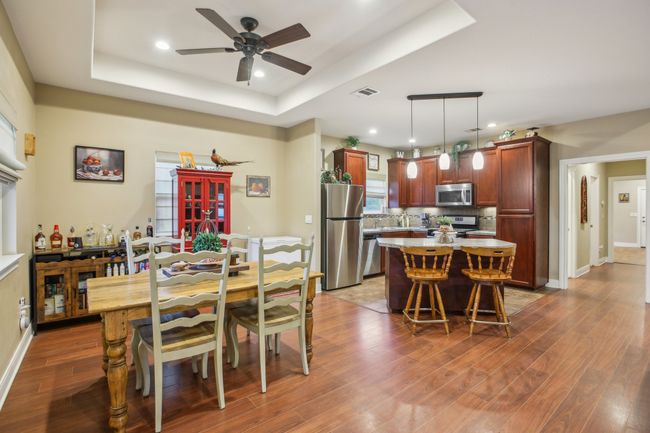 Dining space with ceiling fan, dark hardwood / wood-style floors, and a raised ceiling | Image 14