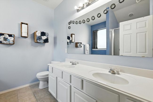 Bathroom featuring double vanity, an enclosed shower, and tile patterned flooring | Image 9