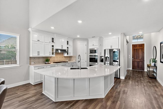 Kitchen featuring white cabinetry, appliances with stainless steel finishes, tasteful backsplash, dark wood-style floors, and recessed lighting | Image 5