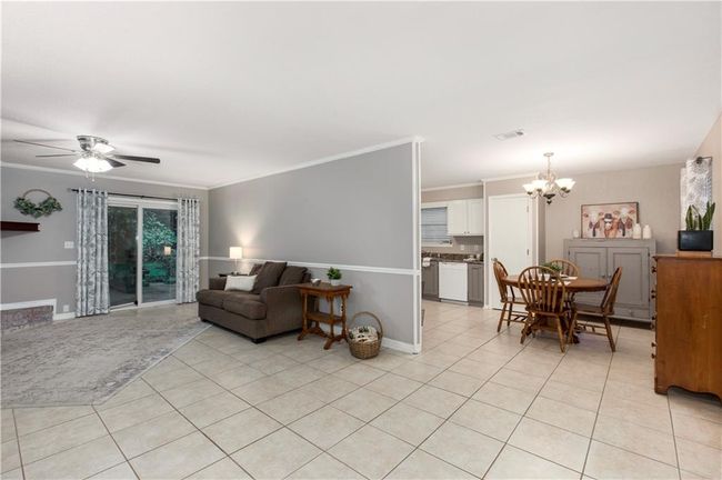 Living room featuring light tile floors, a chandelier, crown molding, and ceiling fan | Image 6