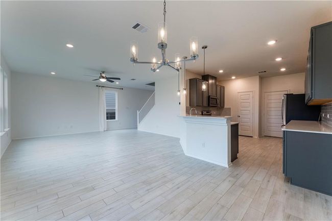 Kitchen featuring a ceiling fan, stainless steel microwave, light countertops, a chandelier, and open floor plan | Image 10