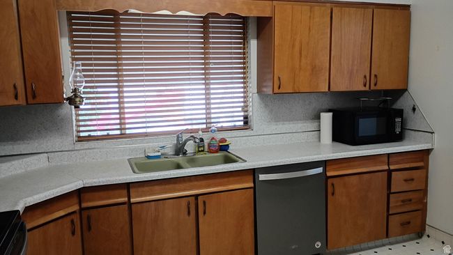 Kitchen with light countertops, black appliances, brown cabinets, and decorative backsplash | Image 19