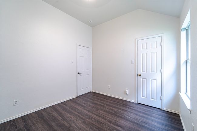 Unfurnished bedroom with dark wood finished floors, lofted ceiling, and multiple windows | Image 34