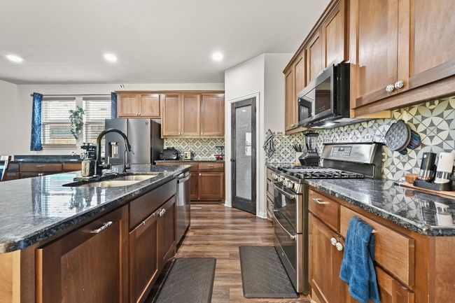 Kitchen with appliances with stainless steel finishes, dark wood finished floors, backsplash, granite countertops, and recessed lighting | Image 7