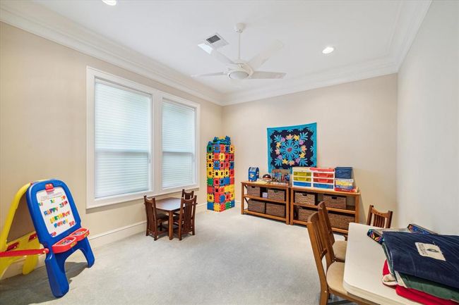 Bright and inviting playroom with neutral walls, carpeted floor, and ample natural light from large windows. | Image 25