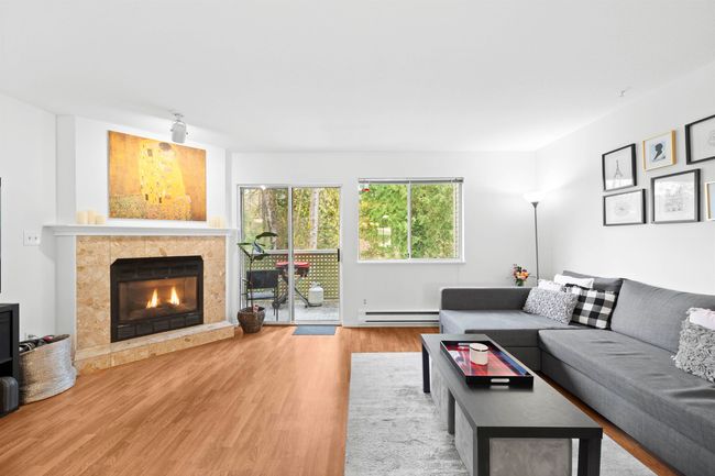 Living room featuring a fireplace, wood finished floors, and baseboard heating | Image 14