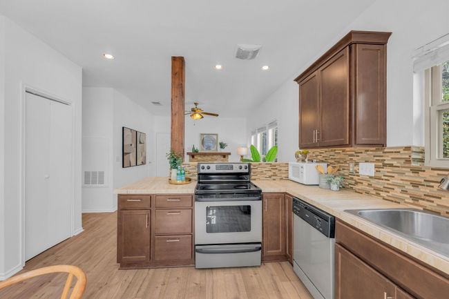 Kitchen featuring appliances with stainless steel finishes, plenty of natural light, light wood-style flooring, light countertops, and recessed lighting | Image 11