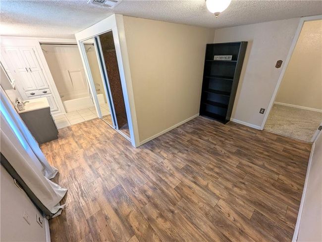 Corridor with wood finished floors, a textured ceiling, and baseboards | Image 18