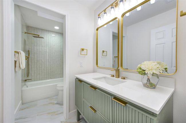 The secondary bathroom has been completely updated with new tile, a modern vanity, and Quartz countertops. A shower/tub combo with updated fixtures offers functionality while maintaining the home’s fresh and modern aesthetic. | Image 23