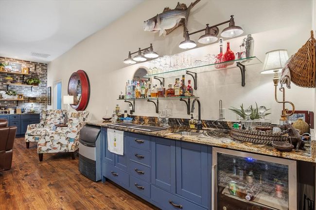 Bar featuring stone counters, dark wood-type flooring, wine cooler, sink, and blue cabinets | Image 33