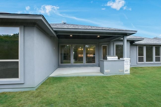 Rear view of property with stucco siding, a yard, and a patio area | Image 29