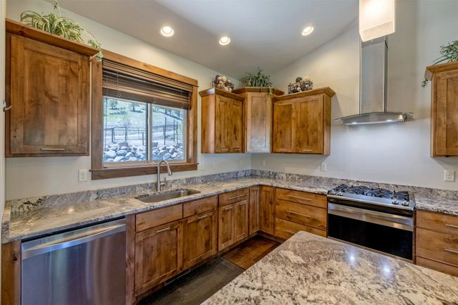 Kitchen featuring appliances with stainless steel finishes, a sink, wall chimney exhaust hood, recessed lighting, and brown cabinets | Image 15