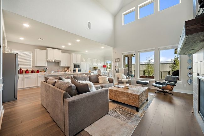 Living area with light wood-style flooring, a towering ceiling, and recessed lighting | Image 12