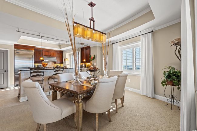 Dining room with ornamental molding, light carpet, and a raised ceiling | Image 17