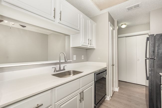 Kitchen with black appliances, a sink, light wood finished floors, white cabinetry, and light countertops | Image 12