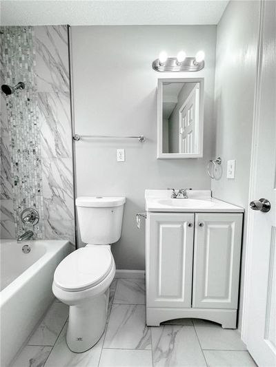 Full bathroom with tile flooring, a textured ceiling, tiled shower / bath, vanity, and toilet | Image 2