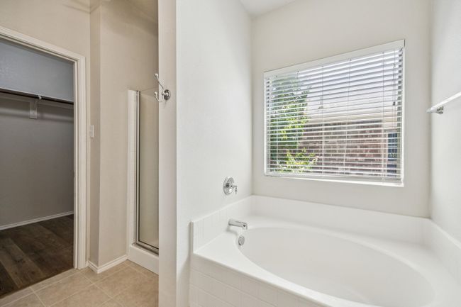 Full bath with a garden tub, a walk in closet, a stall shower, and tile patterned floors | Image 19