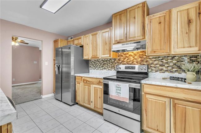 Kitchen with light brown cabinetry, appliances with stainless steel finishes, and under cabinet range hood | Image 21