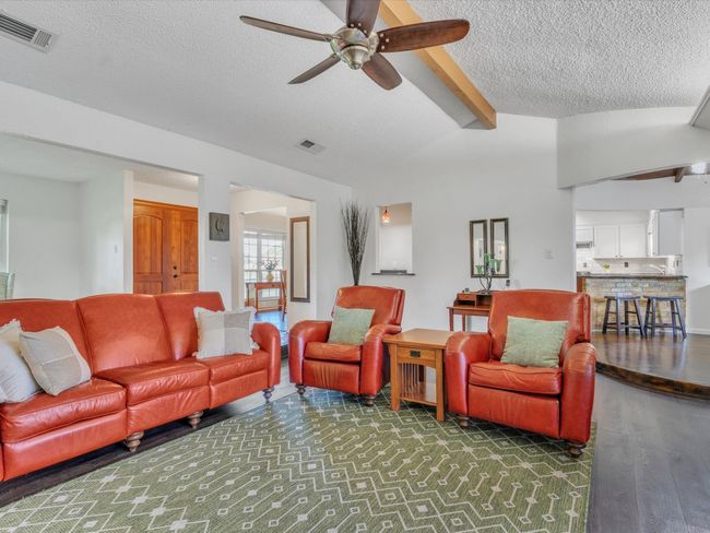 Living room with ceiling fan, a textured ceiling, and wood finished floors | Image 11