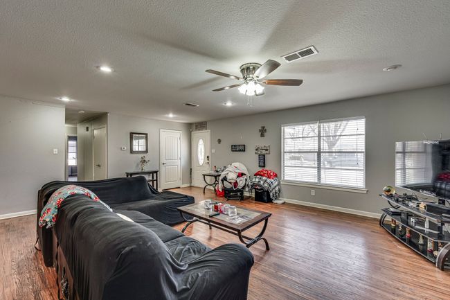 Living room featuring visible vents, baseboards, ceiling fan, wood finished floors, and a textured ceiling | Image 9