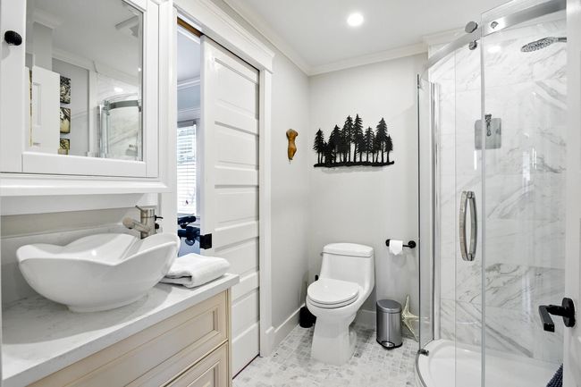 Full bath featuring a marble finish shower, crown molding, baseboards, toilet, and vanity | Image 15