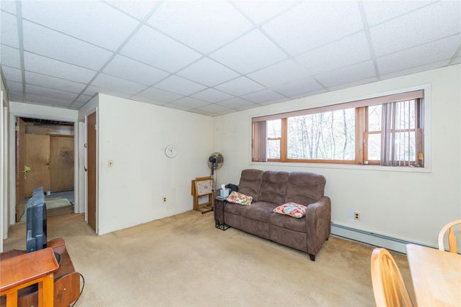 Living area featuring a paneled ceiling, light carpet, and baseboard heating | Image 32