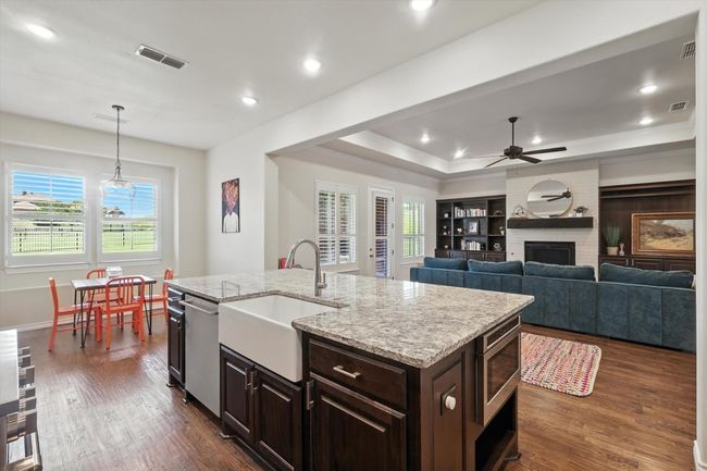 Kitchen with stainless steel appliances, a ceiling fan, dark brown cabinetry, a raised ceiling, and dark wood-type flooring | Image 15
