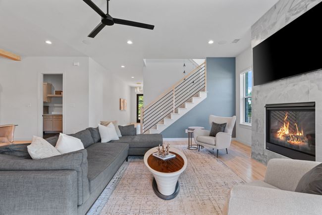 Living area featuring wood finished floors, recessed lighting, a high end fireplace, stairs, and a ceiling fan | Image 12