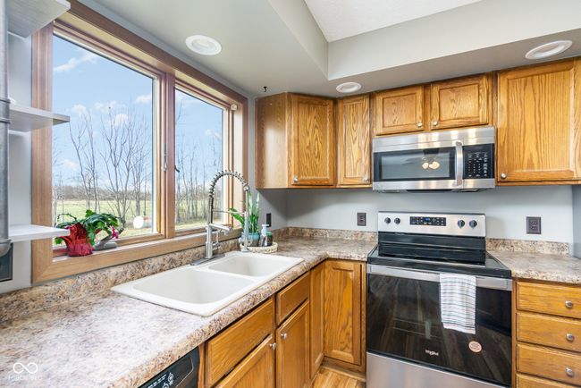 kitchen featuring light countertops, a sink, stainless steel appliances, and brown cabinetry | Image 7