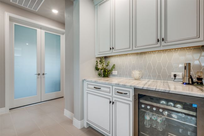 Bar with light tile patterned floors, beverage cooler, light stone countertops, and tasteful backsplash | Image 6