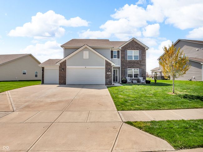 traditional-style home featuring concrete driveway, a front yard, brick siding, and a garage | Image 41