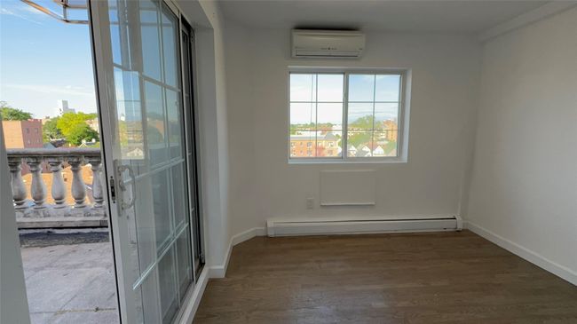 Empty room featuring a wall mounted air conditioner, a baseboard radiator, and wood finished floors | Image 10