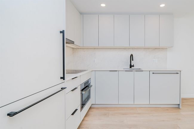 Kitchen featuring light countertops, backsplash, modern cabinets, oven, and a sink | Image 5