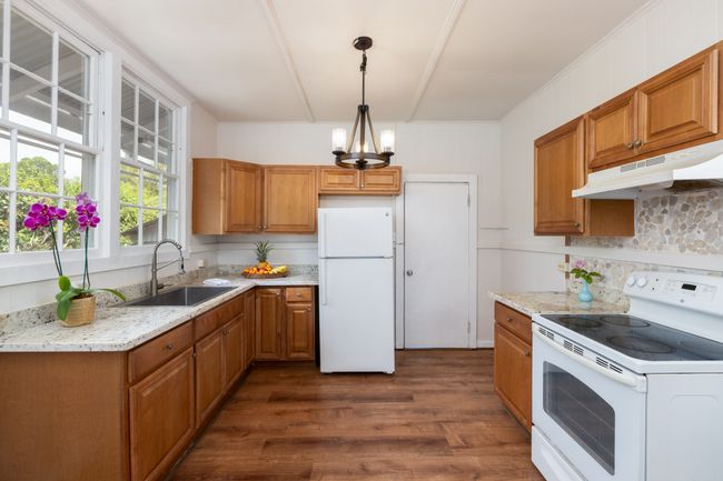 Nice roomy kitchen with good cabinet space, granite counter tops, door goes to downstairs bathroom and on out to the back yard. | Image 4