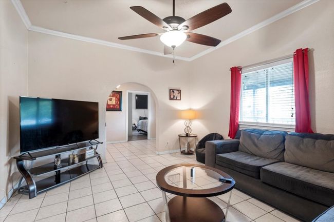 Living area featuring crown molding, light tile patterned flooring, ceiling fan, and arched walkways | Image 4