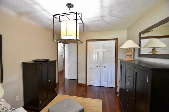 Bedroom with dark wood-type flooring, a textured ceiling, and a closet | Image 17